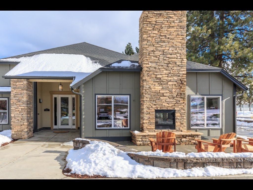 a house with a stone fireplace and a patio with chairs